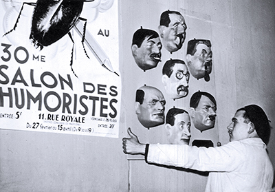 Przygotowania do wystawy artystów-humorystów w Paryżu w lutym 1937 r. Na karykaturalnych maskach przedstawiono m.in. Adolfa Hitlera, Benito Mussoliniego i Leona Bluma Fot. NAC